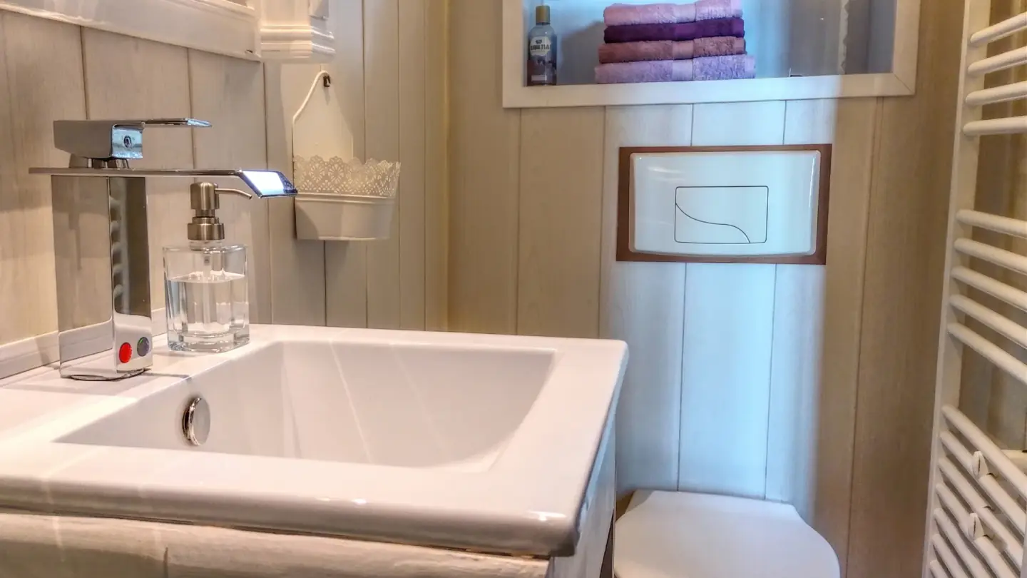 Lavabo moderne et sèche-serviettes dans une salle d’eau de l’Ancienne École.