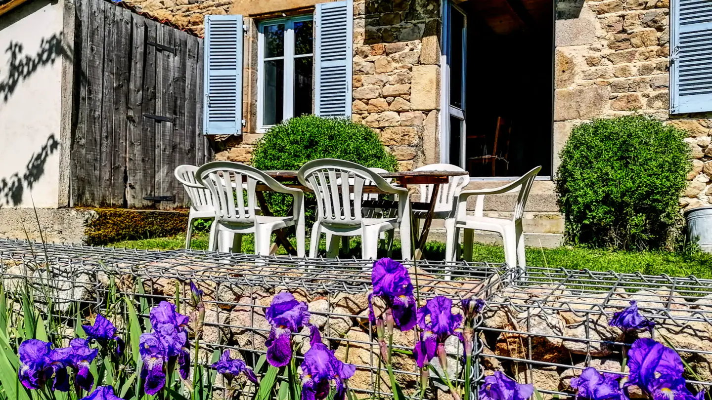 Table extérieure devant la façade en pierre et les volets bleus de Maison Marthe.